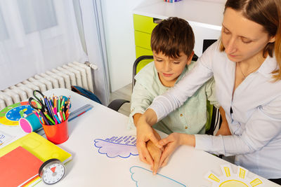 High angle view of therapist teaching autistic boy