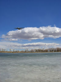 View on a frozen lake with a low flying airplane and an unrecognizable person on the lake