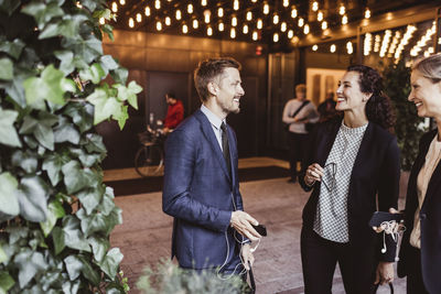 Male entrepreneur smiling with coworkers while standing at building entrance