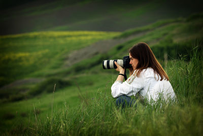 Woman photographing on field