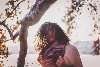 Portrait of young woman standing by lake against sky