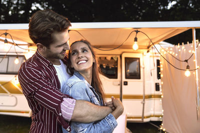 Portrait of couple embracing against camper van