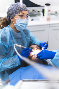 Dentist wearing protective eyewear examining patient in clinic