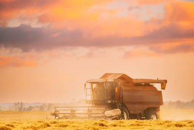 Barn on field against sky during sunset