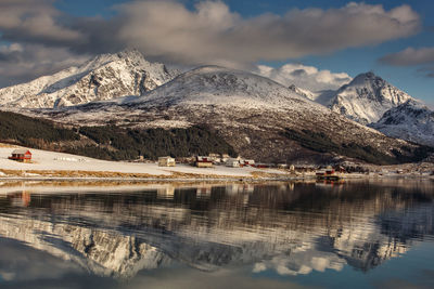 Scenic view of lake by snowcapped mountains against sky