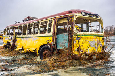 Abandoned bus on field against sky