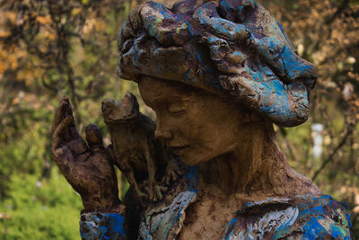 Close-up of old statue against trees