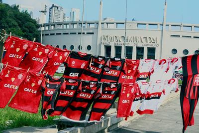 Red flags hanging on street in city against sky