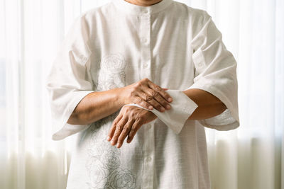 Midsection of man holding hands standing against curtain