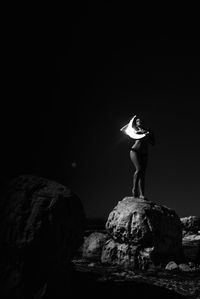 Man standing on rock formation against clear sky at night