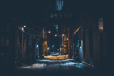 Road amidst buildings in city at night during winter