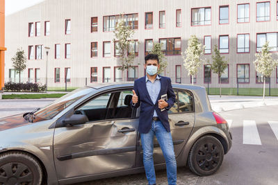 Man standing by car on street in city