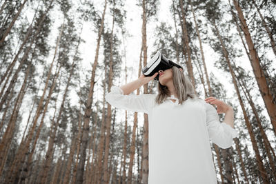 Woman wearing virtual reality simulator against trees outdoors