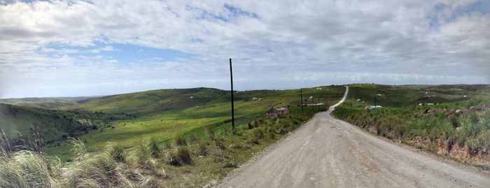 Road amidst field against sky