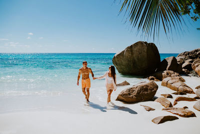 Smiling couple walking while holding hands at beach