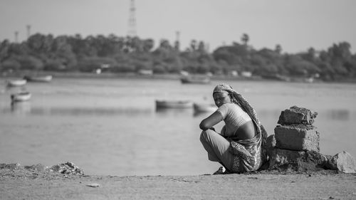 Woman crouching at riverbank