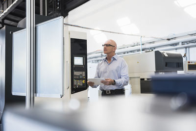 Man with tablet at machine on factory shop floor