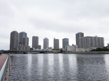 City at waterfront against cloudy sky