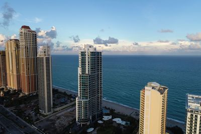 Modern buildings by sea against sky