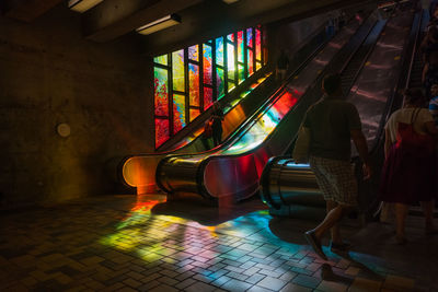 Rear view of people walking towards escalators