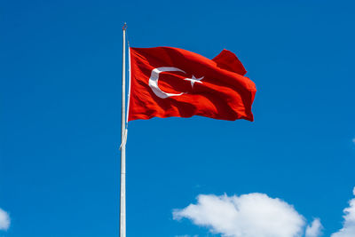 Low angle view of flag against blue sky