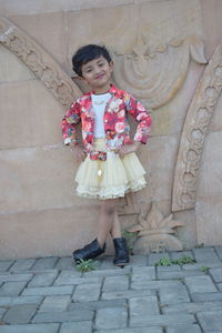 Portrait of smiling girl standing against brick wall