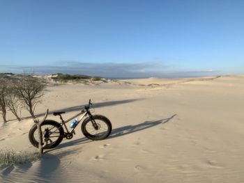 Bicycle parked on desert against clear blue sky