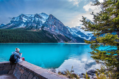 People looking at lake by mountains against sky