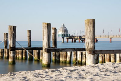 Wooden posts on pier over sea against clear sky