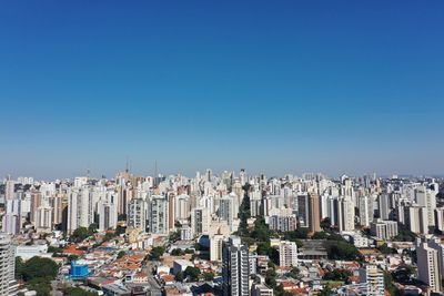 Aerial view of buildings in city against blue sky