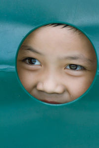 Close-up of boy peeking through circle shape