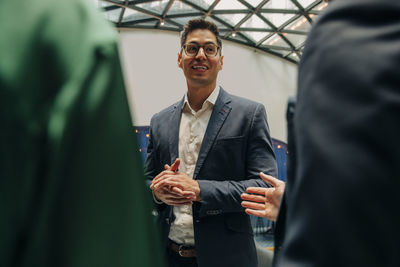 Smiling businessman discussing with male and female colleagues in hotel