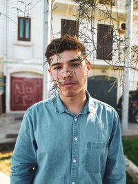 Portrait of young man standing against building