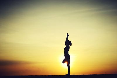 Side view of silhouette woman exercising against sunset