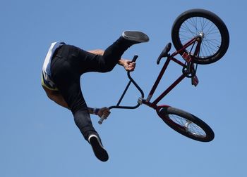 Low angle view of man with bicycle performing a stunt