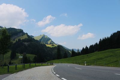 Road leading towards mountains against sky