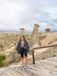 Rear view of woman standing on rock against sky