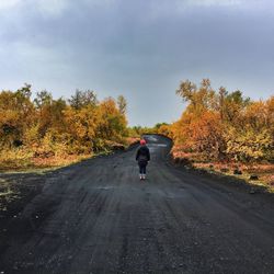 Man riding bicycle on country road against clear sky