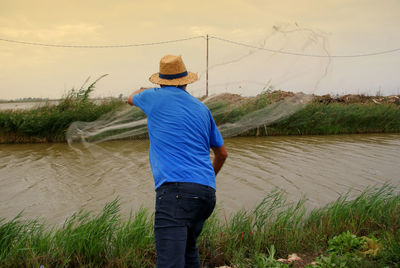 Rear view of man fishing in river