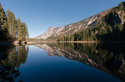 Scenic view of lake by mountains against clear blue sky