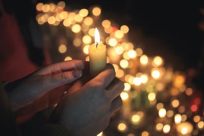 Midsection of woman holding illuminated christmas lights at night