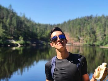 Portrait of man wearing sunglasses against lake