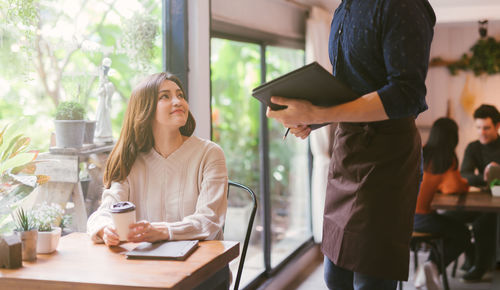 Young woman standing on table at cafe