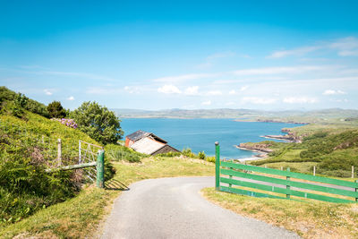 Scenic view of road by sea against sky