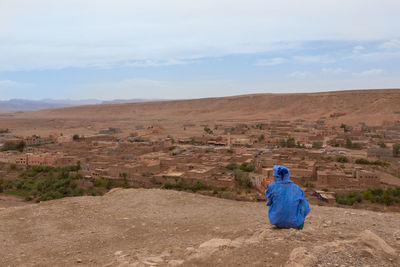 Rear view of a man on landscape against blue sky