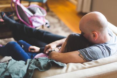 High angle view of father sitting with daughter on sofa