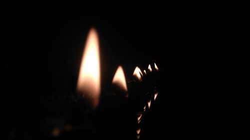 Close-up of burning candle against black background