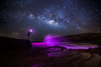 Man standing on beach against sky at night