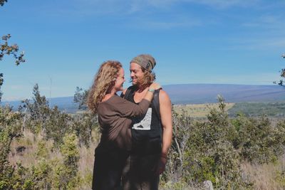 Happy couple standing on mountain against blue sky