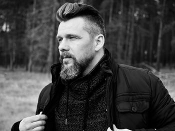 Man looking away while standing against trees